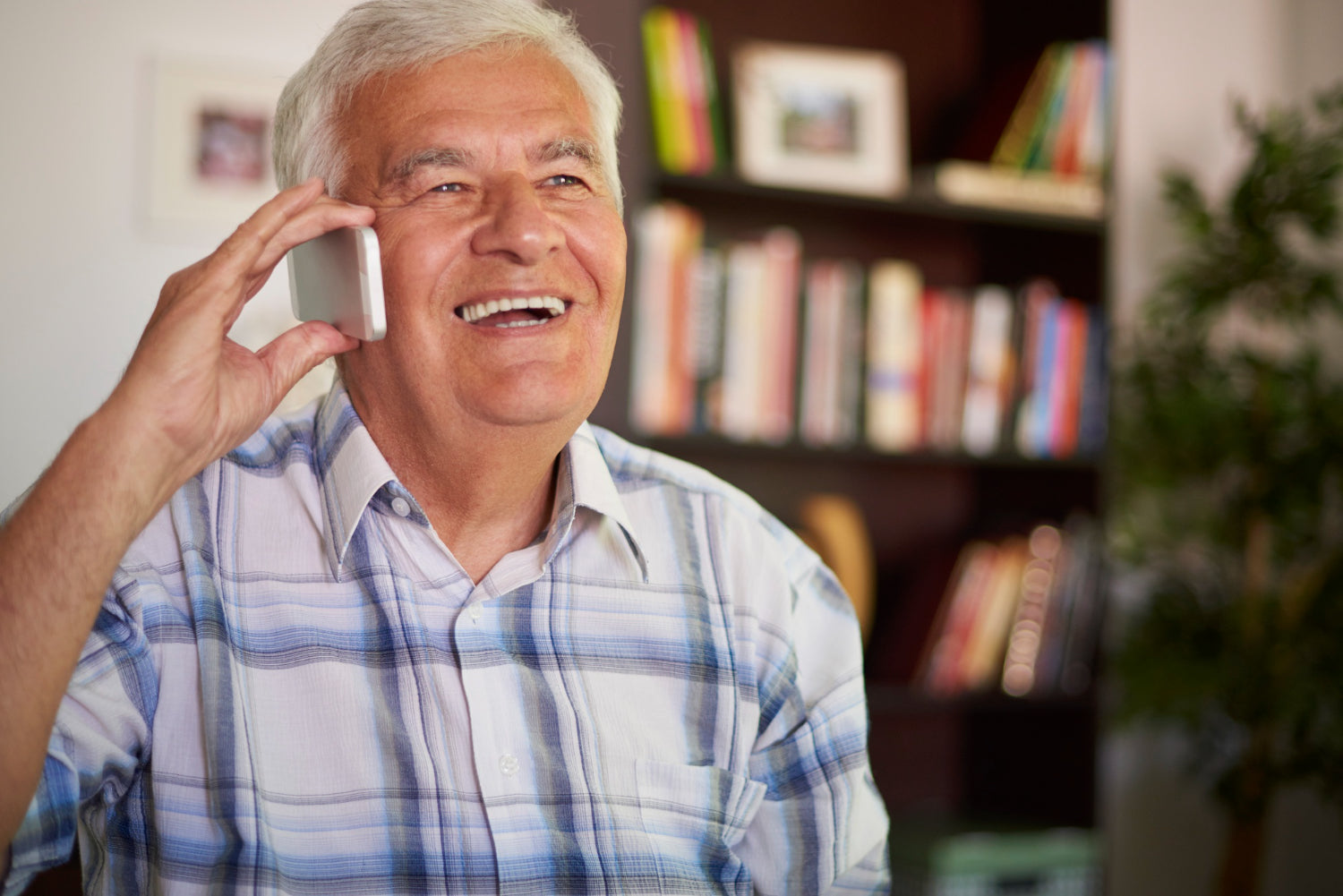 Man talking on a phone with a bookshelf in the background