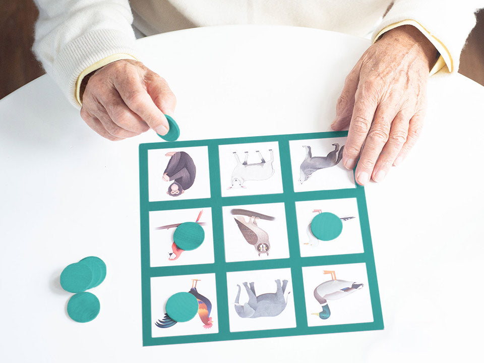 Elderly hands placing a turquoise bingo chip to their bingo card.