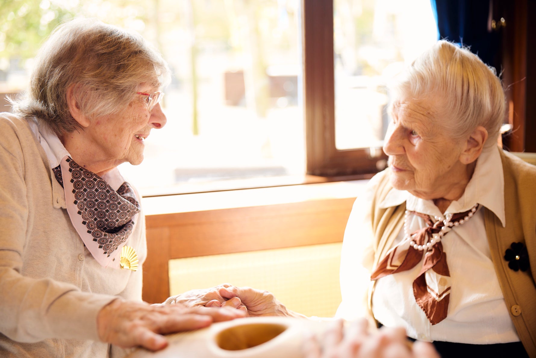Two elderly women sitting together, smiling and engaged in a Crdl interaction