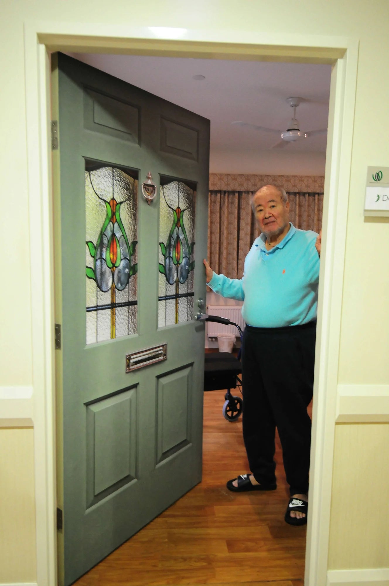 Man standing in his residences room, with a True Doors decal on his door 