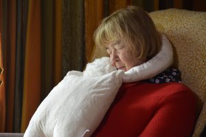 Woman sitting in a chair with the HUG companion wrapped around her shoulders.