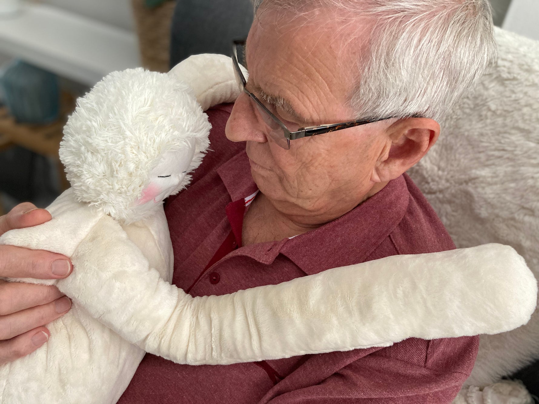 Older man holding the HUG, the sensory companion, designed for people living with dementia.