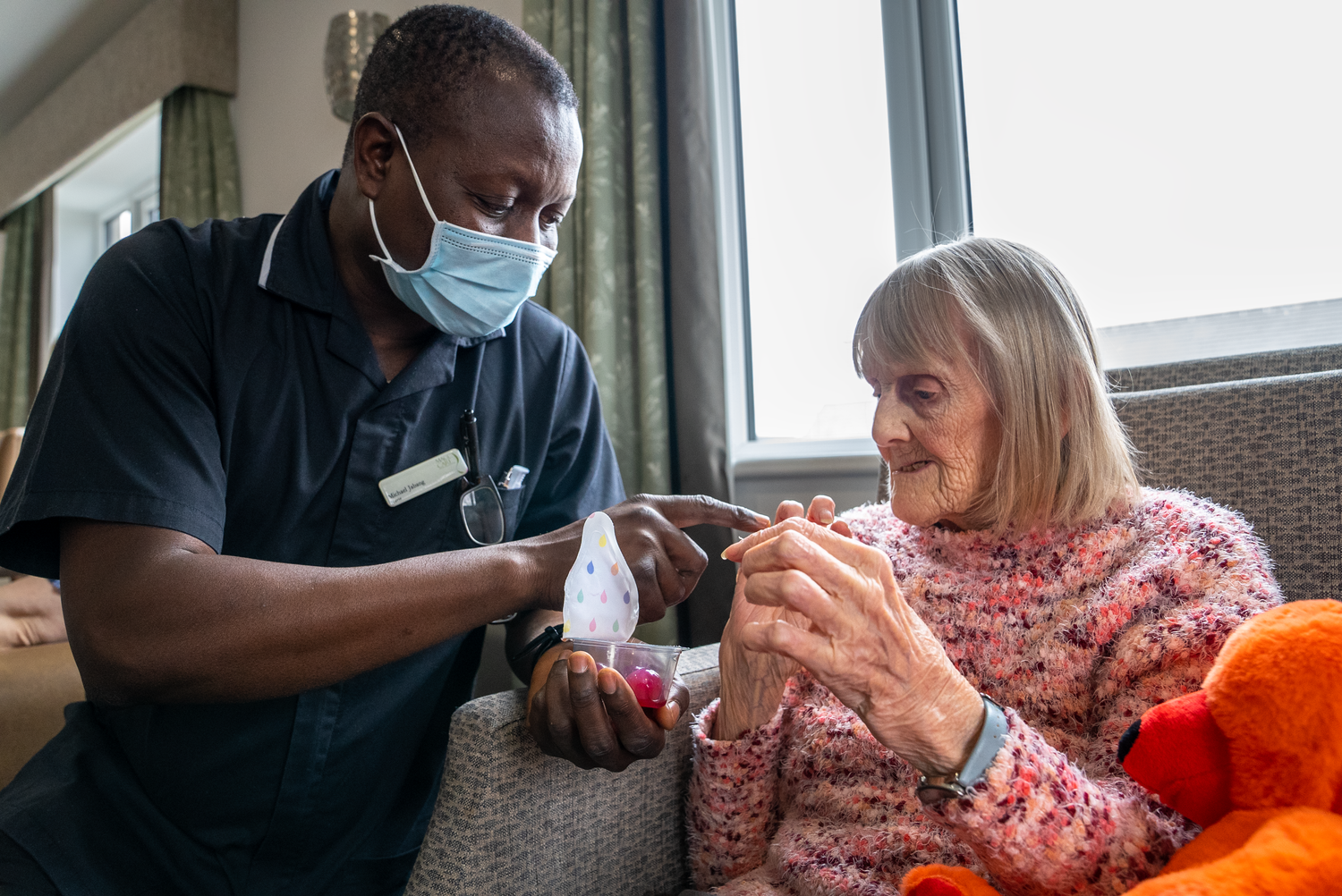 Health Care Profession helping an elderly woman use jelly drops to hydrate herself.