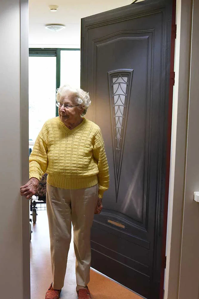 Woman in a yellow sweater standing in front of a True Doors decal 