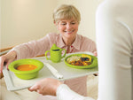 A woman receiving a plate of adaptive tableware