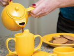 Someone pouring tea out of the Yellow Two Handles Teapot