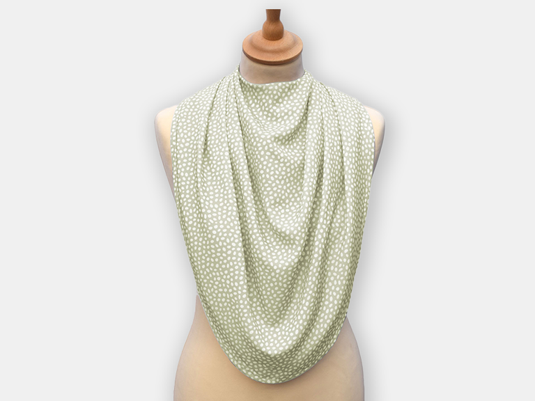 Protective pashmina bib for older adults in the light green with white polka dots pattern.