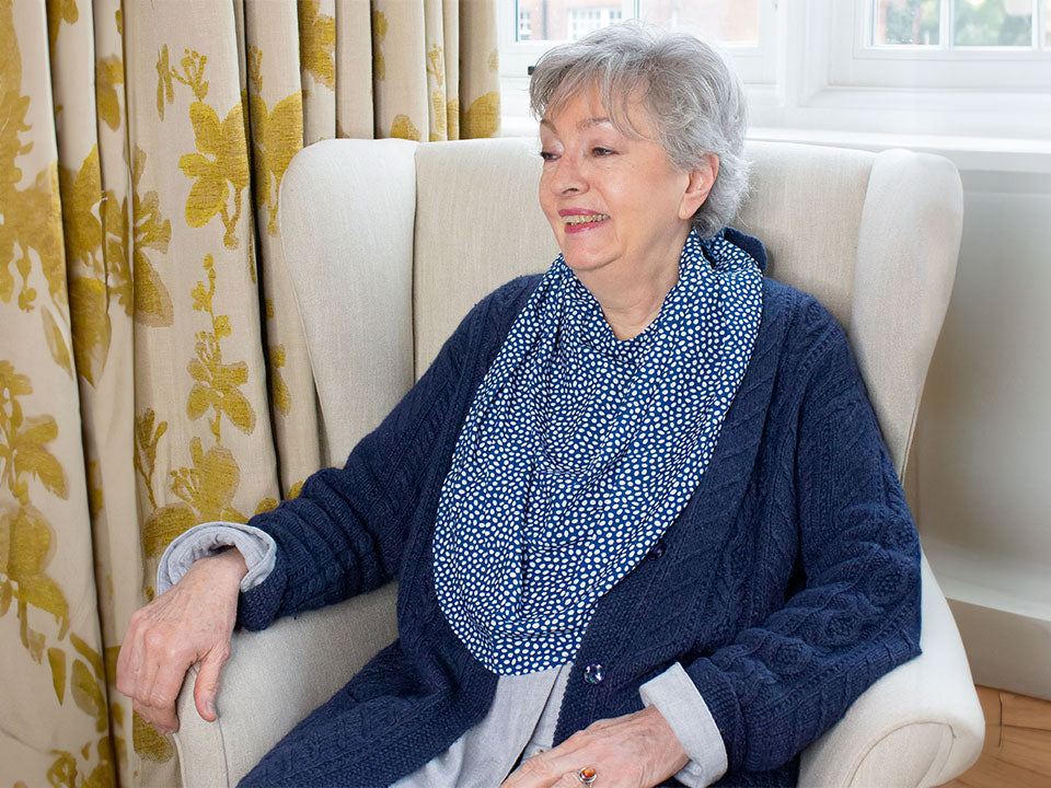 Elderly woman wearing the protective pashmina bib in the burgundy with white polka dots pattern.