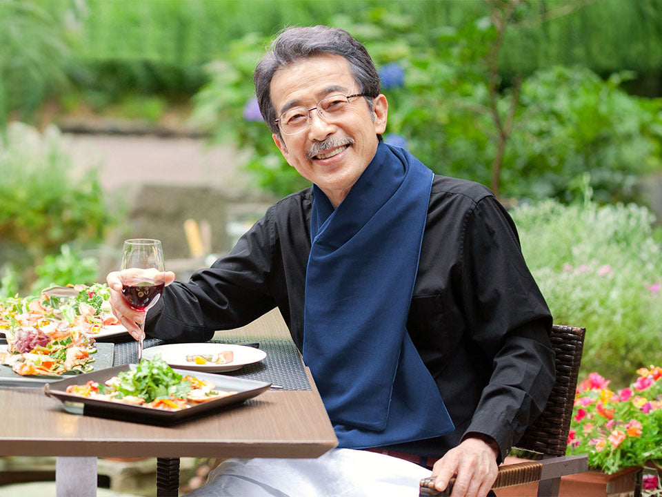 Older man eating a meal with wine on a patio while wearing the protective scarf bib.