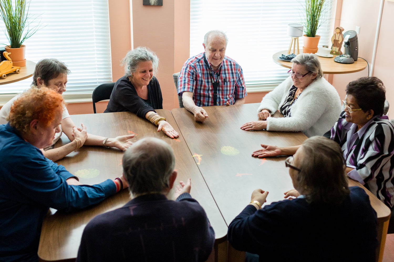 A group of elderly residents around a large table, playing the games projected on to it by the Tovertafel.