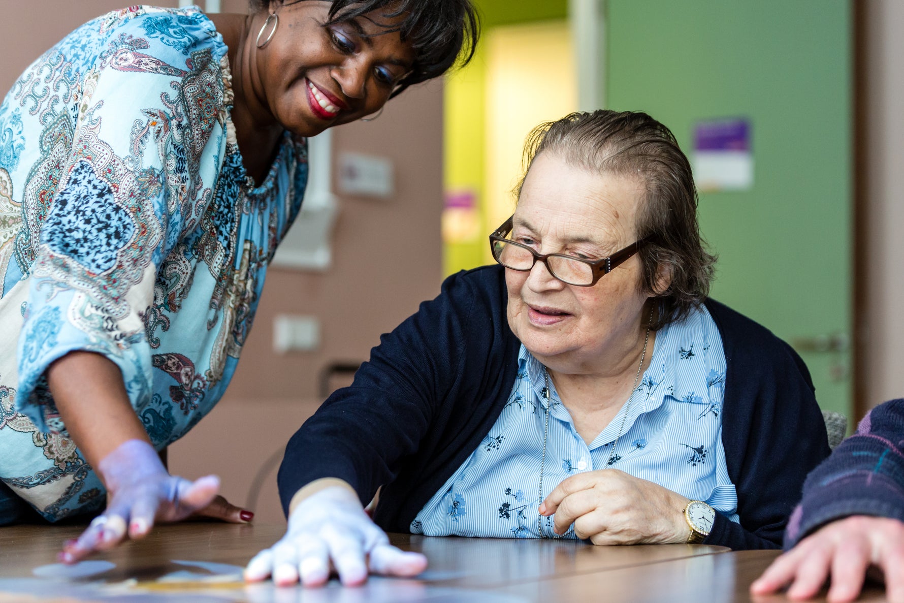 Two women interacting with the Tovertafel  with a focus on engagement and support.