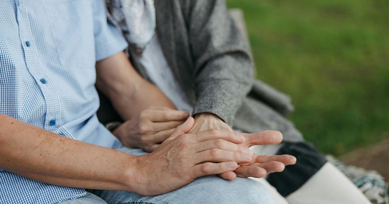 Two older adults holding hands in a park