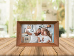Familink 7-inch digital frame placed on a table showing a woman with her daughter and granddaughter taking a selfie.