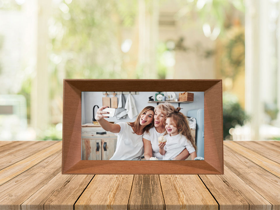 Familink 7-inch digital frame placed on a table showing a woman with her daughter and granddaughter taking a selfie.