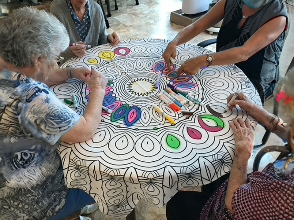A group of elderly residents coloring a Bimoo washable mandala tablecloth.