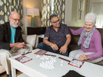 Three elderly people enjoying and playing the accessible Scrabble Bingo game.