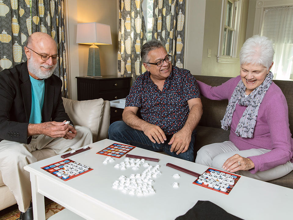 Three elderly people enjoying and playing the accessible Scrabble Bingo game.