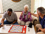 Two middle-aged adults and an elderly woman smiling while playing the inclusive and adapted Scrabble Bingo.