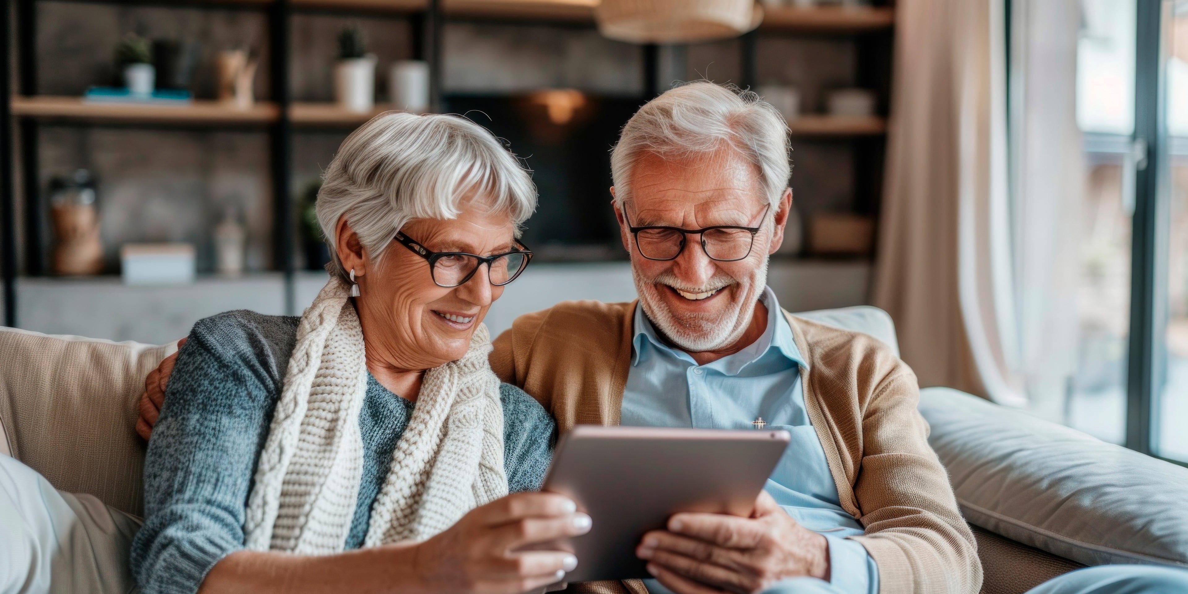 Senior couple using a tablet together on a couch in a home setting