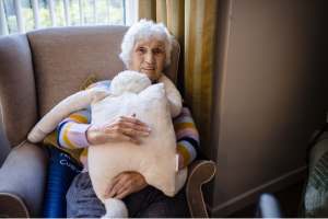 Woman holding the HUG companion on a couch in a home setting