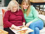 An older woman and her caregiver, sitting on a couch, doing an adapted 13-piece Relish puzzle together.