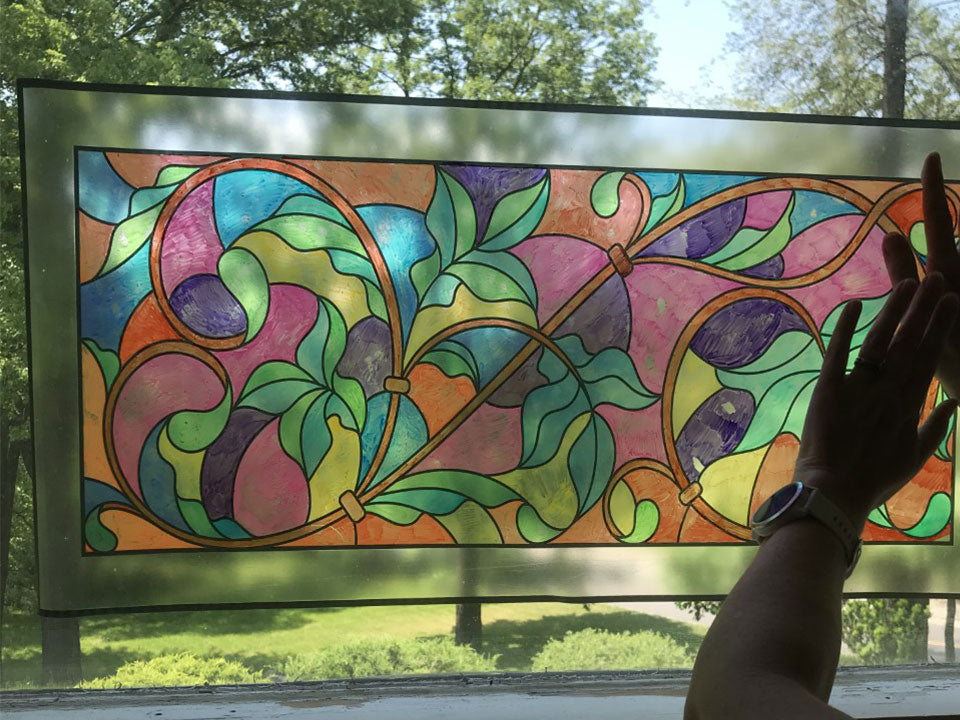 Zoom on the hands of a person sticking a colored transom of a window.