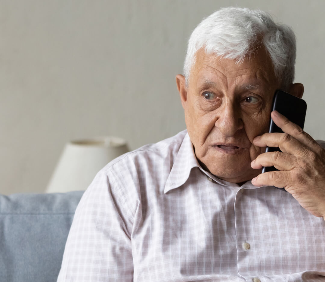 Man with white hair talking on a phone indoors