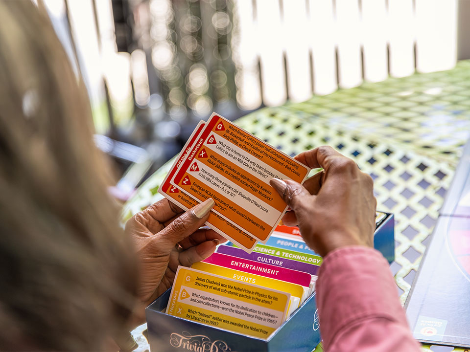 Over the shoulder view of a senior women holding trivial pursuit generation easy to read cards.