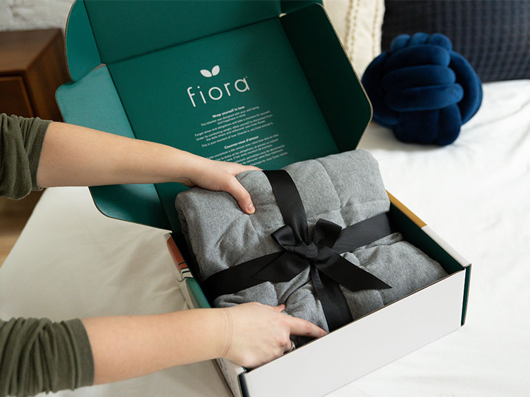 Person unboxing the Fiora weighted sensory blanket.